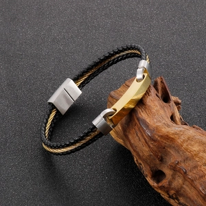 Detail of men's braided rope bracelet with gold-plated metal plate on a wooden branch
