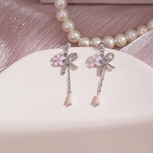 Vue détaillée de boucles d'oreilles fleurs roses à pompons avec strass sur socle blanc