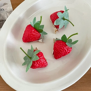 Set of 4 3D strawberry hair clips with green leaves on white plate and wooden desk