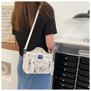Detailed view of white motorcycle jacket shaped crossbody bag with silver studs and zippers