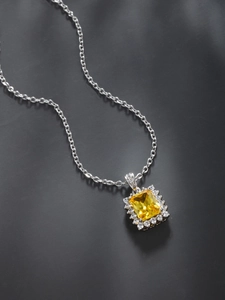Detail of silver necklace with square yellow gemstone pendant and zircon border