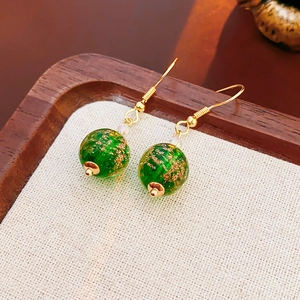 Detailed macro view of green glass beads with gold specks on premium earrings set