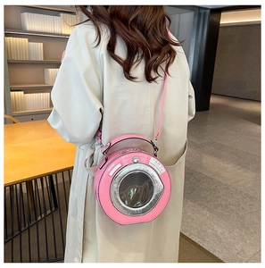 Detail view of the pink circular crossbody bag with laundry machine design on a trench coat
