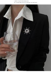 Detail of 18k gold plated sunburst brooch with pavé zircon worn on a black blazer