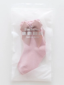 Pink Lolita style baby socks with large bow in a semi-transparent frosted zipper bag