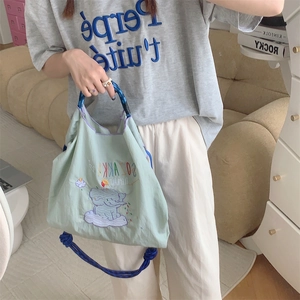 Detailed close-up of cute elephant embroidery and blue rope handles on green tote bag