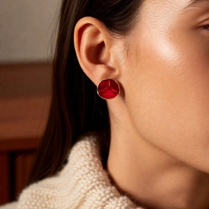 Close-up of red enamel round earring with gold trim on model for vintage jewelry set