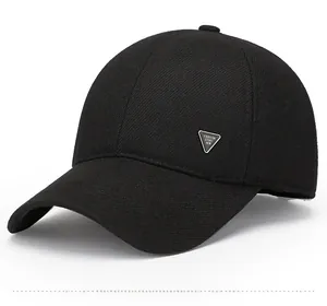 Detail view of black wool-like baseball cap with a silver triangle fashion metal logo badge