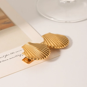 Vue détaillée de pinces à cheveux dorées en forme de coquillage en acier plaqué or 18K