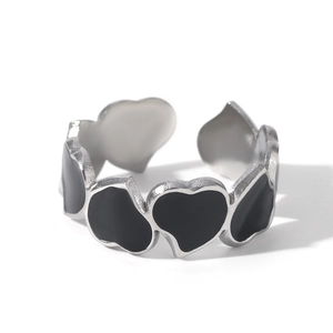 Detailed close-up of a silver stainless steel open ring with black enamel heart patterns