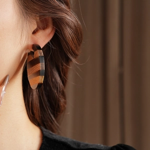 Close-up of heart-shaped wooden drop earrings with striped texture on female model