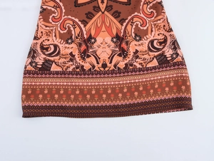 Détail de l'imprimé paisley bohème sur une robe courte aux motifs orange et marron vifs