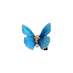 Barrette papillon en acrylique bleu avec base dorée, strass et pendentif en perle