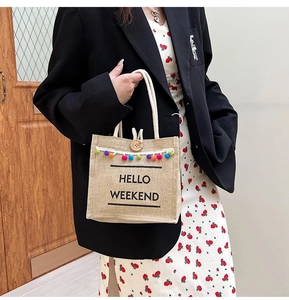 Macro shot of jute tote bag with colorful pom-pom trim and Hello Weekend print