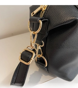 Detail of bright gold metal hook and D-ring on high-quality black lychee leather bag