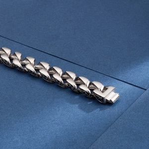 Detail of silver stainless steel Cuban link bracelet with lobster clasp on blue background