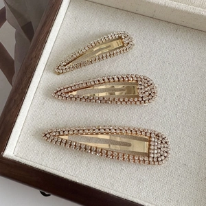 Three-piece gold alloy hair clip set with sparkling rhinestones on a textured tray