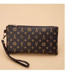 Close-up detail of dark brown vintage patterned handbag with gold zipper and wrist strap