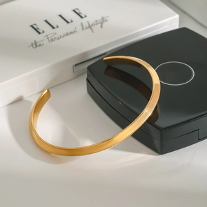 Close-up of a minimalist 18K gold-plated stainless steel cuff bracelet on a gift box