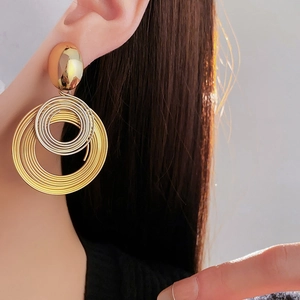 Detailed view of layered spiral hoop earrings in gold and silver mixed metal finish