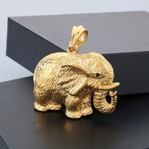 Close-up of golden elephant pendant with textured skin detail and dark gemstone eyes