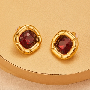 Macro detail of retro golden square earrings featuring central red facet stones