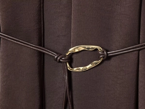 Détail de la taille d'une robe en satin avec cordon en cuir marron et boucle dorée