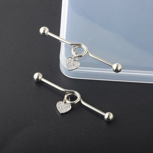 Detailed view of silver industrial barbell earrings with rhinestone heart charms