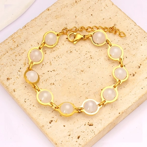 Close-up of golden link bracelet with eleven milky white round stones and lobster clasp