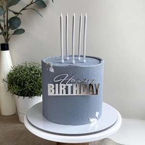 Silver Happy Birthday acrylic topper and candles on a dusty blue frosted cake