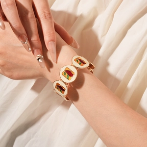 Detail of vintage gold bracelet with colorful enamel inlay worn on wrist