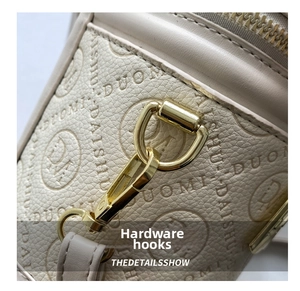 Detailed close-up of golden metal hooks and brand embossed lychee grain leather bag