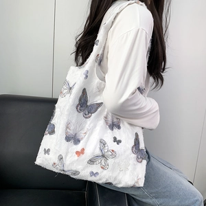 Détail du sac cabas en jacquard blanc avec imprimé papillon et texture à bords effilochés