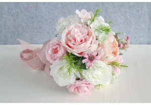 Close-up of artificial bridal bouquet with pink roses, peonies and silk ribbon detail