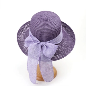 Close-up of deep purple straw sun hat featuring a large lavender linen bow detail