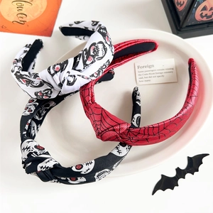 Three Halloween knotted headbands with skull and spider web patterns on a tray