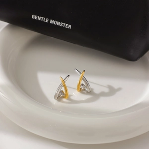Detail view of two-tone gold and silver stainless steel earrings on white ceramic