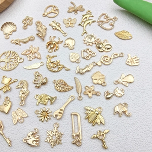 Macro display of various golden metal pendants including musical notes and mermaid shapes