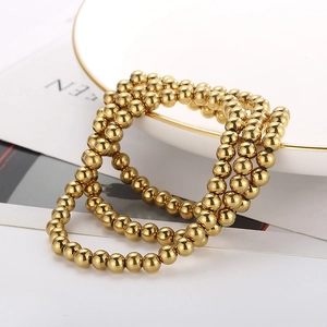 Detailed view of three-piece gold bead elastic bracelet set on a ceramic tray