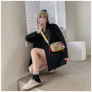 Macro shot of graffiti crossbody bag with bold text and yellow patterned wide strap