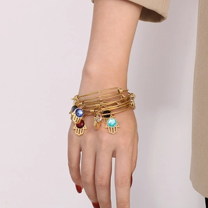 Dettaglio del set di bracciali Hamsa dorati regolabili con gemme colorate al polso