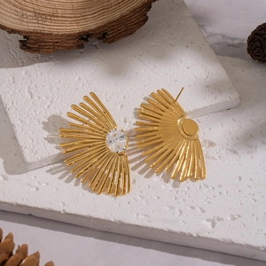 Boucles d'oreilles soleil dorées avec zircon sur fond de pierre minimaliste chic