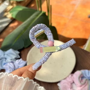 Detail of light blue plaid hair claw clip with pink bead and pencil-shaped pendant charm