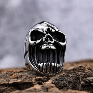 Punk style screaming skull ring in mechanical stainless steel on a textured wood background