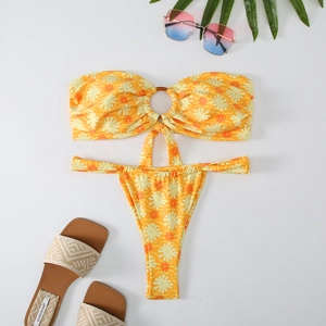 Flat lay of yellow daisy print bandeau bikini with ring detail and summer accessories