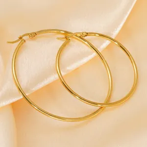Polished 18K gold plated stainless steel hoop earrings on champagne silk fabric background