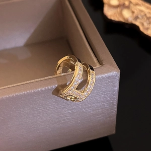 Macro shot of gold D-shaped earring with zircon pavé on a jewelry box edge