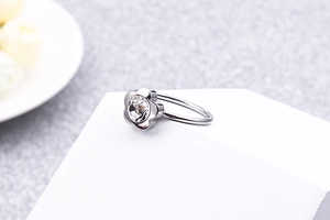 Macro view of silver flower ring with sparkling zircon stone on a white display stand