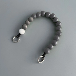 Close-up of gray and white wooden beads phone strap with metal ring clasps on gray background