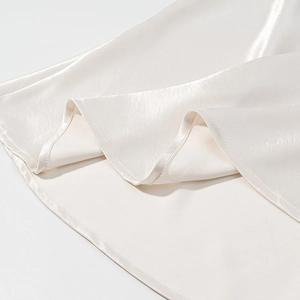 Detail of premium pearl white satin fabric showing smooth texture and fine sewing edge